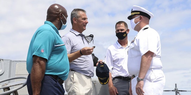 Urban Meyer hands a ceremonial coin to Cmdr. Matthew McKenna.