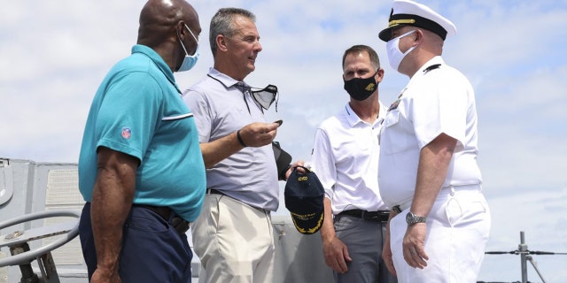 Urban Meyer hands a ceremonial coin to Cmdr. Matthew McKenna.