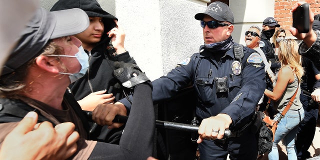 Les agents de police de Huntington Beach tentent de séparer les partisans lors d'un rassemblement Black Lives Matter et White Lives Matter dimanche à Huntington Beach.  (Wally Skalij / Los Angeles Times via Getty Images)