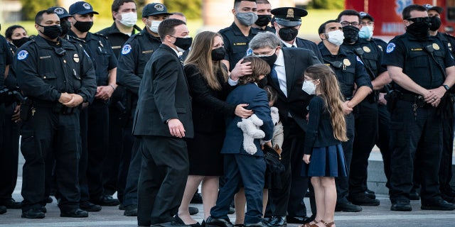 Family members hug after the casket of Evans was carried from the Capitol on Tuesday. (AP/The Washington Post)