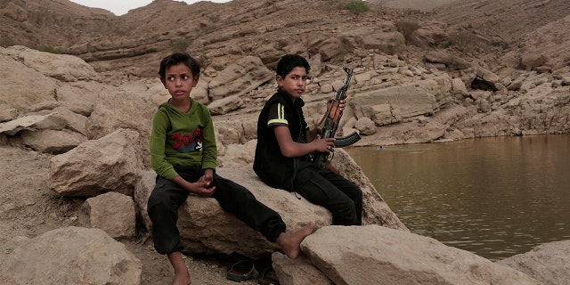 In this July 30, 2018 photo, a 17-year-old boy holds his weapon at the dam in Marib, Yemen. 