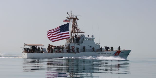 Coast Guardsmen aboard the U.S. Coast Guard cutter USCGC Adak raise the American flag. (U.S. Coast Guard photo by Seaman Frank Iannazzo-Simmons/Released)