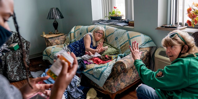 March 17, 2021: Sue Howland, right, and Larrecsa Cox, left, members of the Quick Response Team whose mission is to save every citizen who survives an overdose from the next one, help Betty Thompson, 65, who struggles with alcohol addiction, count her medications at her apartment in Huntington, W.Va.