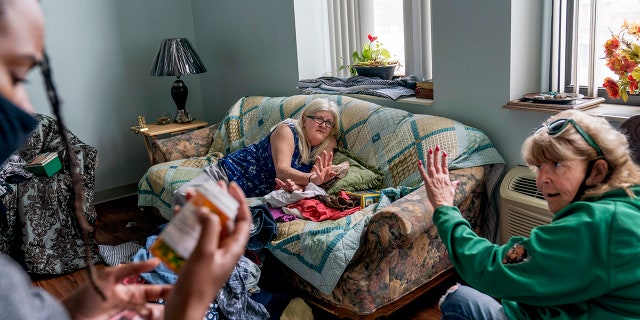 March 17, 2021: Sue Howland, right, and Larrecsa Cox, left, members of the Quick Response Team whose mission is to save every citizen who survives an overdose from the next one, help Betty Thompson, 65, who struggles with alcohol addiction, count her medications at her apartment in Huntington, W.Va.