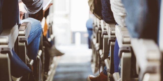 The cabin of a commercial airliner, packed full of passengers.  Health experts advise people to get up and move from time to time on long flights.  Another good tip includes stretching your feet and calves to improve circulation. 