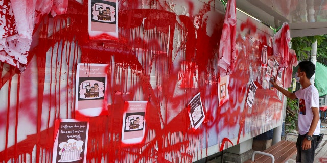 An anti-coup protester uses red paint as he writes slogans at a bus stop on Wednesday April 14, 2021 in Yangon, Burma. Anti-coup protesters kept public demonstrations going despite the threat of lethal violence from security forces. The words reads "We do not accept military coup". (AP Photo)