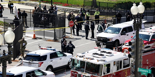 Police and fire officials stand near a car that crashed into a barrier on Capitol Hill in Washington, Friday, April 2, 2021. (AP Photo/J. Scott Applewhite)