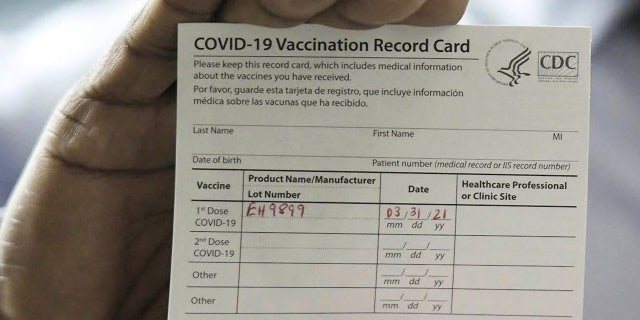 Dr. Leon Haley Jr. the CEO of UF Health Jacksonville shows his COVID-19 vaccination record card shortly before he received the first injection of the COVID-19 vaccine. (Bob Self/Florida Times-Union via AP)