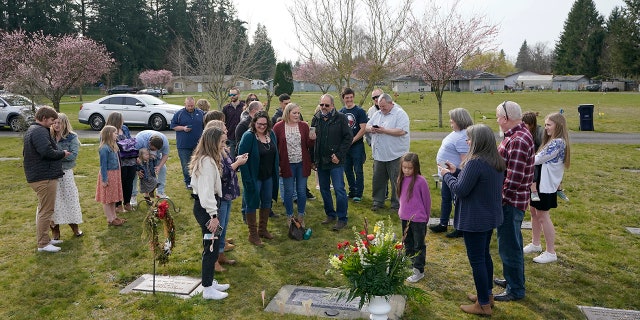 March 27, 2021: Family members and friends sing as they gather around the headstone Carole Rae Woodmansee shares with her husband Jim (who died in 2003) at Union Cemetery in Sedro-Woolley, Wash., north of Seattle, following a memorial service.