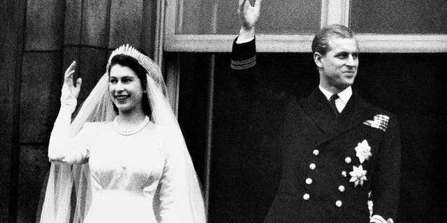 In this Nov. 20, 1947 file photo, Britain's Princess Elizabeth and her husband the Duke of Edinburgh wave to the crowds on their wedding day, from the balcony of Buckingham Palace in London. 