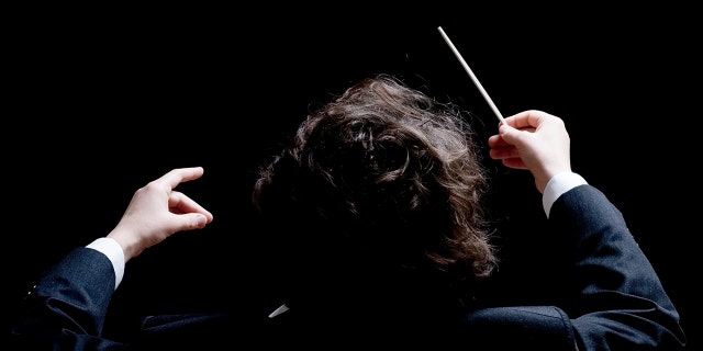A conductor's hands with a baton.