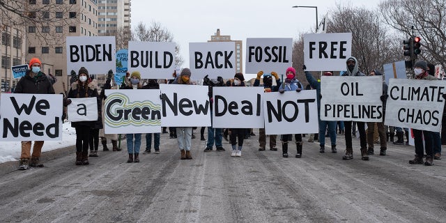 People hold signs calling for President Joe Biden to support a Green New Deal and end his support of pipelines and the fossil fuel industry. St. Paul, MN. January 29, 2021. (Photo by Tim Evans/NurPhoto via Getty Images)
