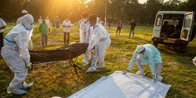 Municipal workers prepare to bury the body of a person who died of COVID-19 in Gauhati, India, Sunday, April 25, 2021. (AP Photo/Anupam Nath)