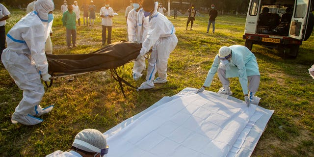 Municipal workers prepare to bury the body of a person who died of COVID-19 in Gauhati, India, Sunday, April 25, 2021. (AP Photo/Anupam Nath)