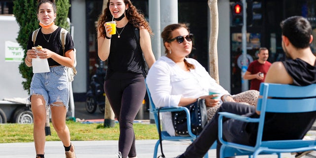 People walk on a street in the Israeli coastal city of Tel Aviv on April 18, 2021, after authorities announced that face masks for COVID-19 prevention were no longer needed outside. (Photo by JACK GUEZ/AFP via Getty Images)