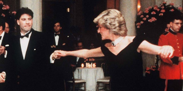 Diana, Princesa de Gales, usando um vestido de veludo azul meia-noite, com ombro largo desenhado por Victor Edelstein, é observada pelo presidente dos EUA Ronald Reagan e pela primeira-dama Nancy Reagan, enquanto ela dança com John Travolta na Casa Branca em 9 de novembro de 1985 em Washington, DC.