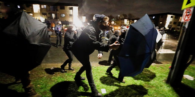 Protesters advance towards officers using umbrellas as shields outside Brooklyn Center Police Department a day after Daunte Wright was shot and killed by a police officer, in Brooklyn Center, Minnesota, April 12, 2021. (REUTERS/Nick Pfosi)