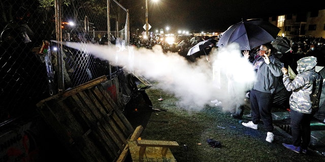 Pepper spray is used from behind the fenced up perimeters of the Brooklyn Center Police Department, as protests continued days after former police officer Kim Potter fatally shot Daunte Wright.