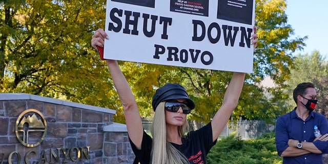 Paris Hilton poses for a photo in front of the Provo Canyon School during a protest Friday, Oct. 9, 2020, in Provo, Utah. Hilton was in Utah Friday to lead a protest outside a boarding school where she alleges she was abused physically and mentally by staff when she was a teenager. Hilton, now 39, went public with the allegations in a new documentary and wants a school that she says left her with nightmares and insomnia for years to be shut down.