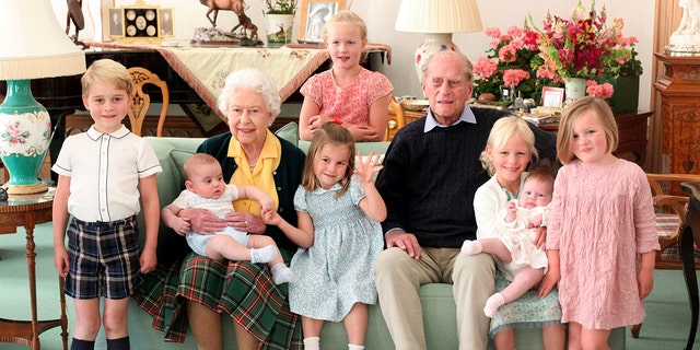 In this undated handout photo provided by the Duke and Duchess of Cambridge, Britain's Queen Elizabeth and Prince Philip pose with their great-grandchildren. From left, Prince George, Prince Louis, Savannah Phillips (standing at rear), Princess Charlotte, Isla Phillips holding Lena Tindall, and Mia Tindall. 