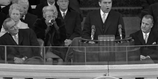 President Richard M. Nixon dedicates his new administration to the cause of "peace among nations" as former President Lyndon Johnson, right, listens to the inaugural speech Jan. 20, 1969 in Washington. Seated at right is Vice President Spiro Agnew and former Vice President Hubert Humphrey.