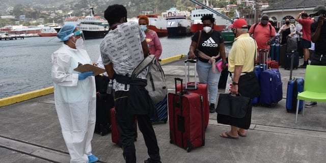 Des ressortissants britanniques, canadiens et américains attendent de monter à bord du navire de croisière Royal Caribbean Reflection pour être évacués gratuitement, à Kingstown, sur l'île de Saint-Vincent, dans les Caraïbes orientales, le vendredi 16 avril 2021 (Crédit: AP Photo / Orvil Samuel)