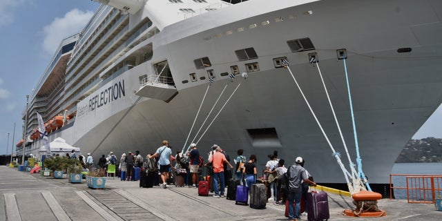 British, Canadian and U.S. nationals line up alongside the Royal Caribbean cruise ship Reflection to be evacuated free of charge, in Kingstown on the eastern Caribbean island of St. Vincent, Friday, April 16, 2021. (AP Photo/Orvil Samuel)