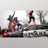 Men jump on police vehicles near the site of a shooting involving a police officer, Sunday, April 11, 2021, in Brooklyn Center, Minnesota.