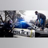 A man stands atop a police car after throwing a brick at the windshield near the site of a shooting involving a police officer, Sunday, April 11, 2021, in Brooklyn Center, Minnesota.