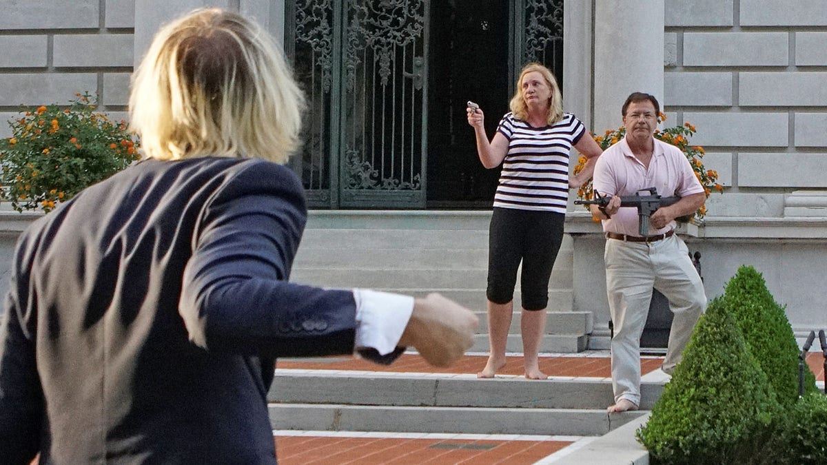 Patricia and Mark McCloskey draw their firearms on protestors as they enter their neighborhood during a protest against St. Louis Mayor Lyda Krewson, in St. Louis, Missouri, U.S. June 28, 2020. Picture taken June 28, 2020. REUTERS/Lawrence Bryant