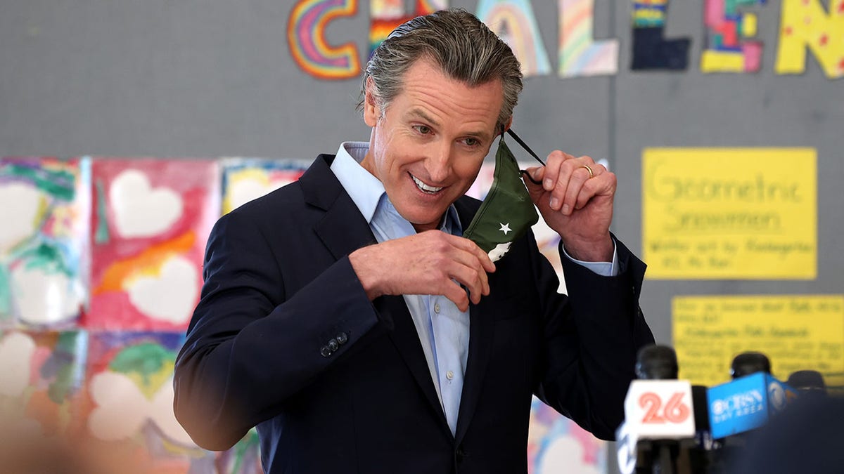 California Gov. Gavin Newsom removing his mask before speaking during a news conference after he toured the newly reopened Ruby Bridges Elementary School on March 16 in Alameda.