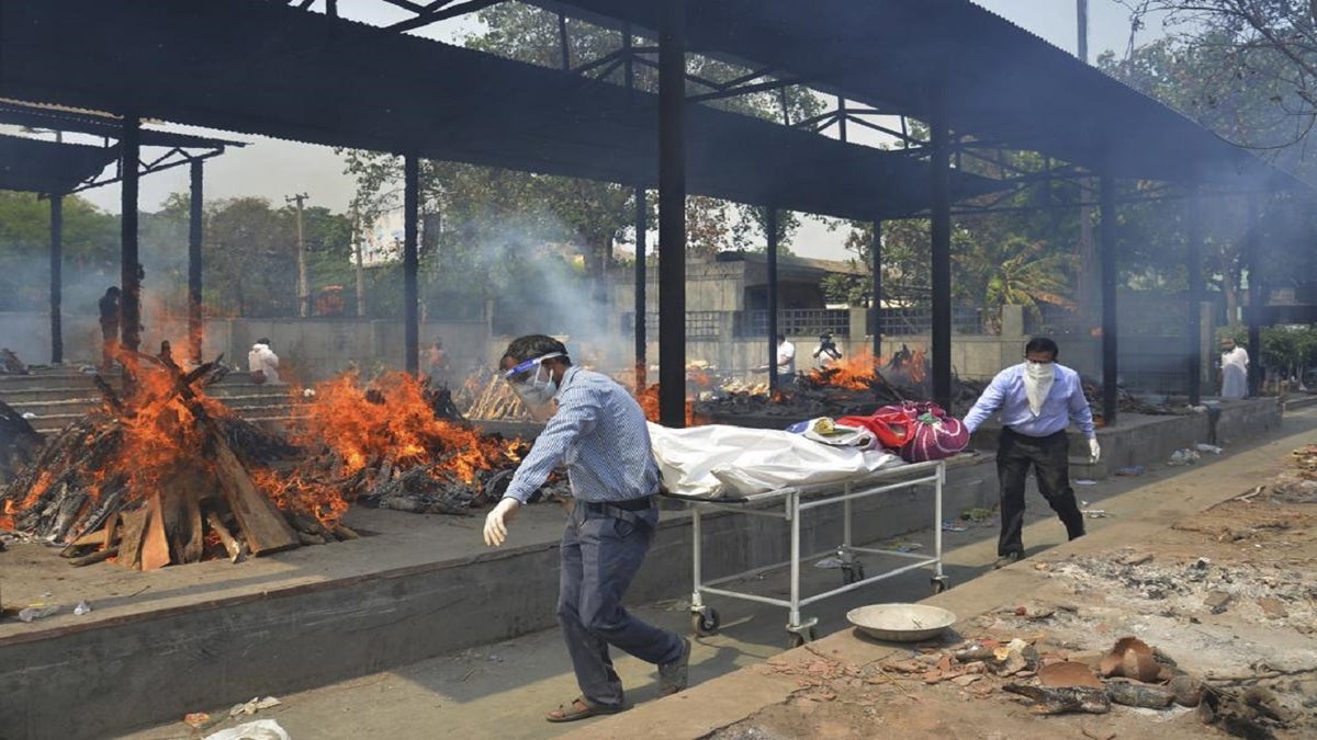 Relatives carry the body of a person who died of COVID-19 as scores of other victims are burned at a crematorium in New Delhi, India, in 2021.