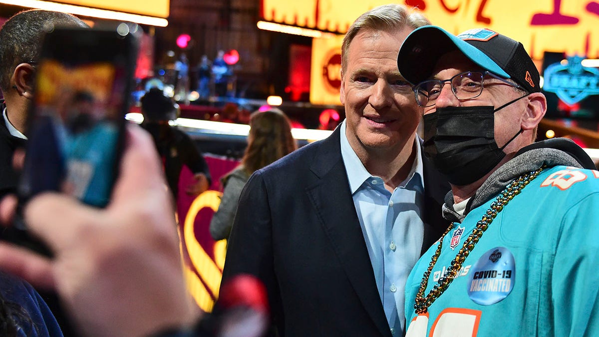 NFL Commissioner Roger Goodell takes photos with fans during the third round of the NFL football draft, Friday, April 30, 2021, in Cleveland. (AP Photo/David Dermer)