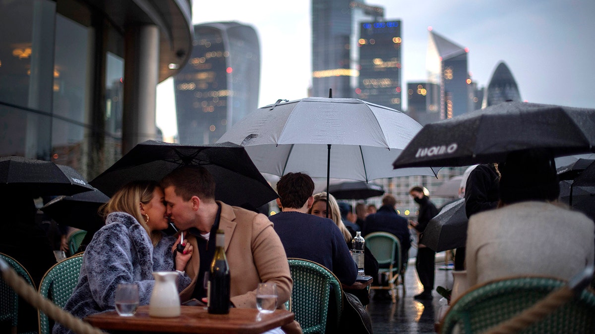 People endure the wet and windy Bank Holiday weekend weather to sit outside a restaurant near Tower Bridge in central London on Monday, May 3, 2021.