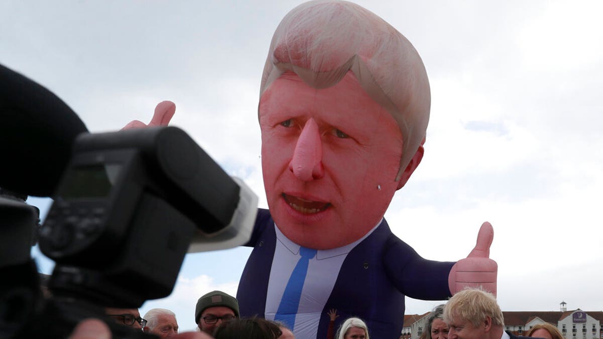 British Prime Minister Boris Johnson speaks to the media next to a large inflatable of him and flanked by Jill Mortimer, the winning Conservative Party candidate of the Hartlepool by-election on May 7, 2021.(AP Photo/Scott Heppell)