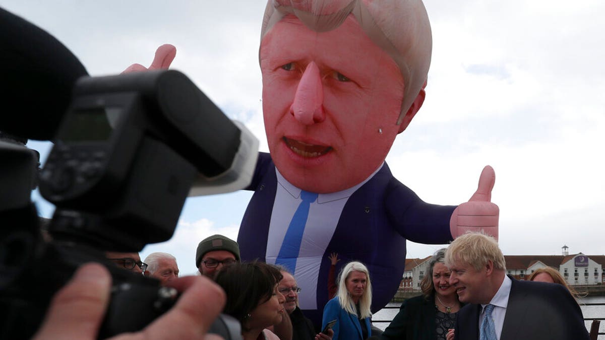 British Prime Minister Boris Johnson speaks to the media next to a large inflatable of him and flanked by Jill Mortimer, the winning Conservative Party candidate of the Hartlepool by-election on May 7, 2021.(AP Photo/Scott Heppell)