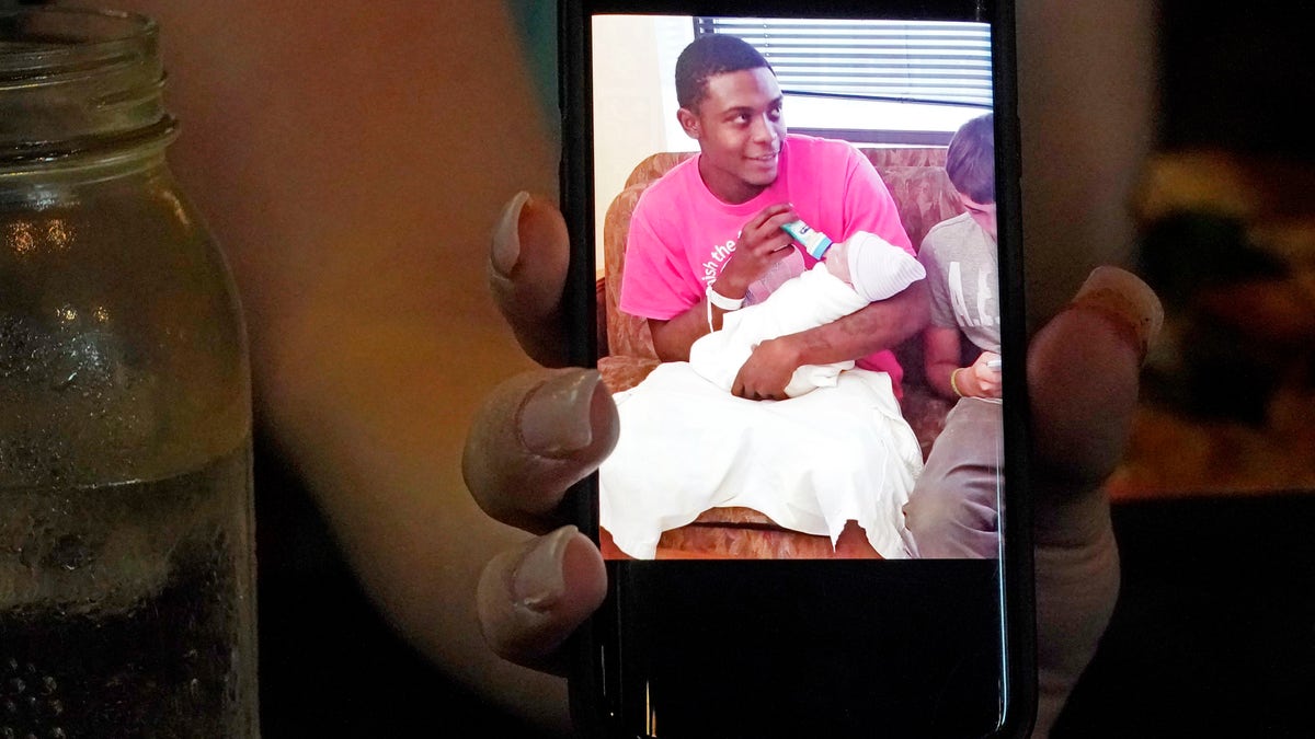 Alexis Rankin holds a 2018 cell phone photograph of her former boyfriend Willie Jones Jr., holding their newborn son, as she recalls the events of February 8, 2018, when Jones was discovered hanging from a tree in the yard of Rankin's family home shortly after arriving there with Rankin. The sheriff's department and the Mississippi Bureau of Investigation, both ruled the death a suicide. However, a Jackson-area judge in April awarded close to $11.4 million to Jones' family in a civil suit claiming wrongful death, alleging that Rankin's stepfather, Harold O'Bryant, Jr., either killed Jones or failed to prevent him from killing himself. (AP Photo/Rogelio V. Solis)