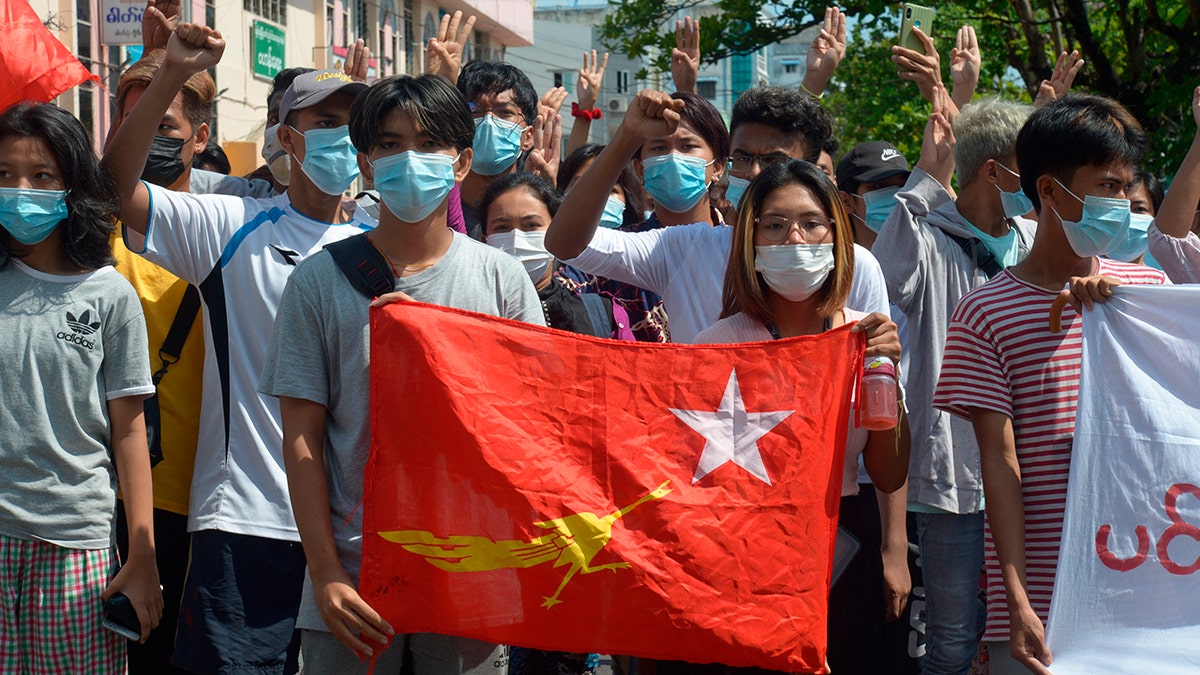 Anti-coup protesters hold the flag of the National League for Democracy party of ousted Myanmar leader Aung San Suu Kyi, while others flash the three-fingered salute during a "flash mob" rally in Bahan township in Yangon, Myanmar, Sunday, May 9, 2021. (AP Photo)