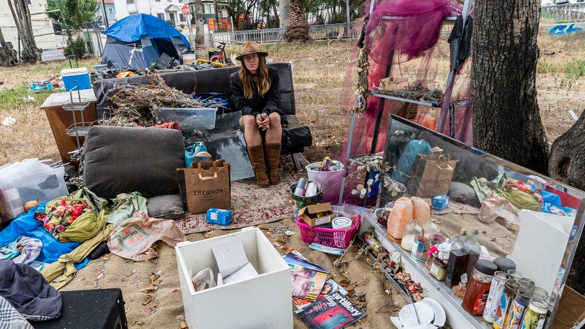 Dawn Woodward, 39, who is homeless and originally from Arizona, sits outdoors in a homeless camp on the side of the CA-101 highway in Echo Park neighborhood in Los Angeles. (AP Photo/Damian Dovarganes)