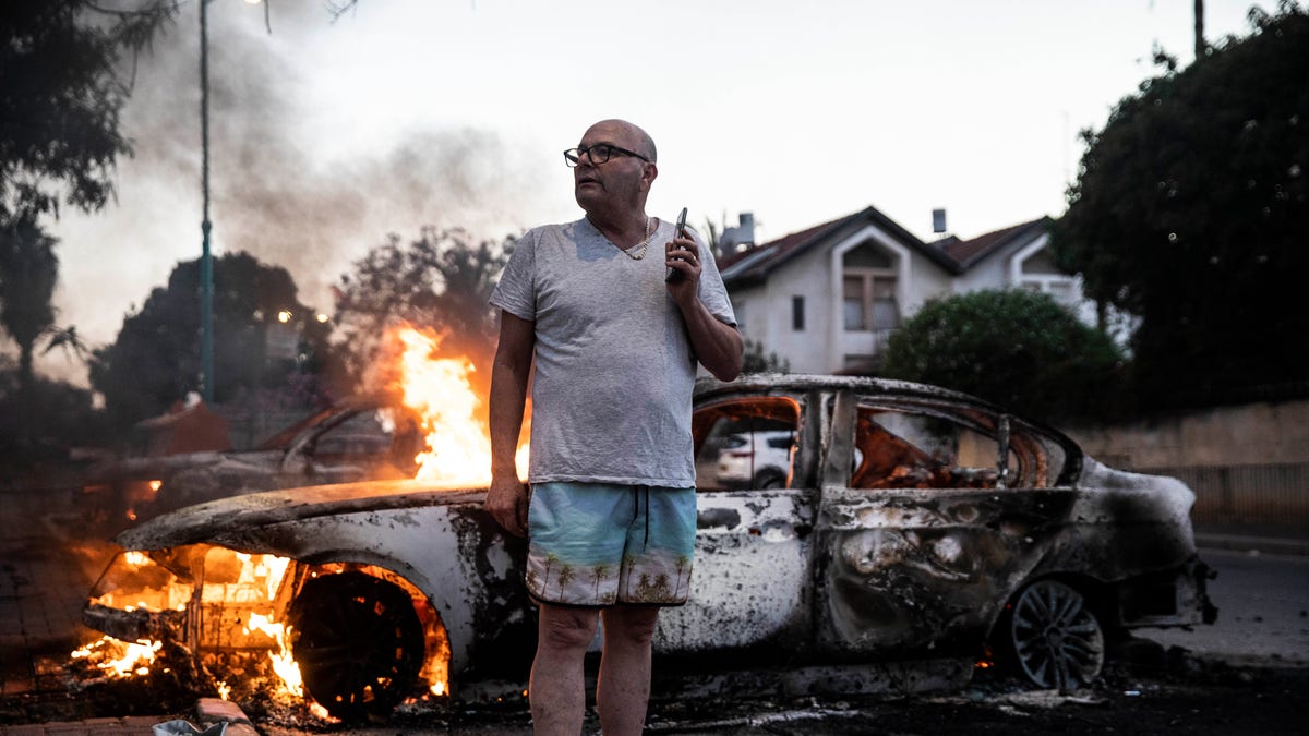 Jacob Simona stands by his burning car during clashes with Israeli Arabs and police in the Israeli mixed city of Lod, Israel Tuesday, May 11,2021. (AP Photo/Heidi Levine)