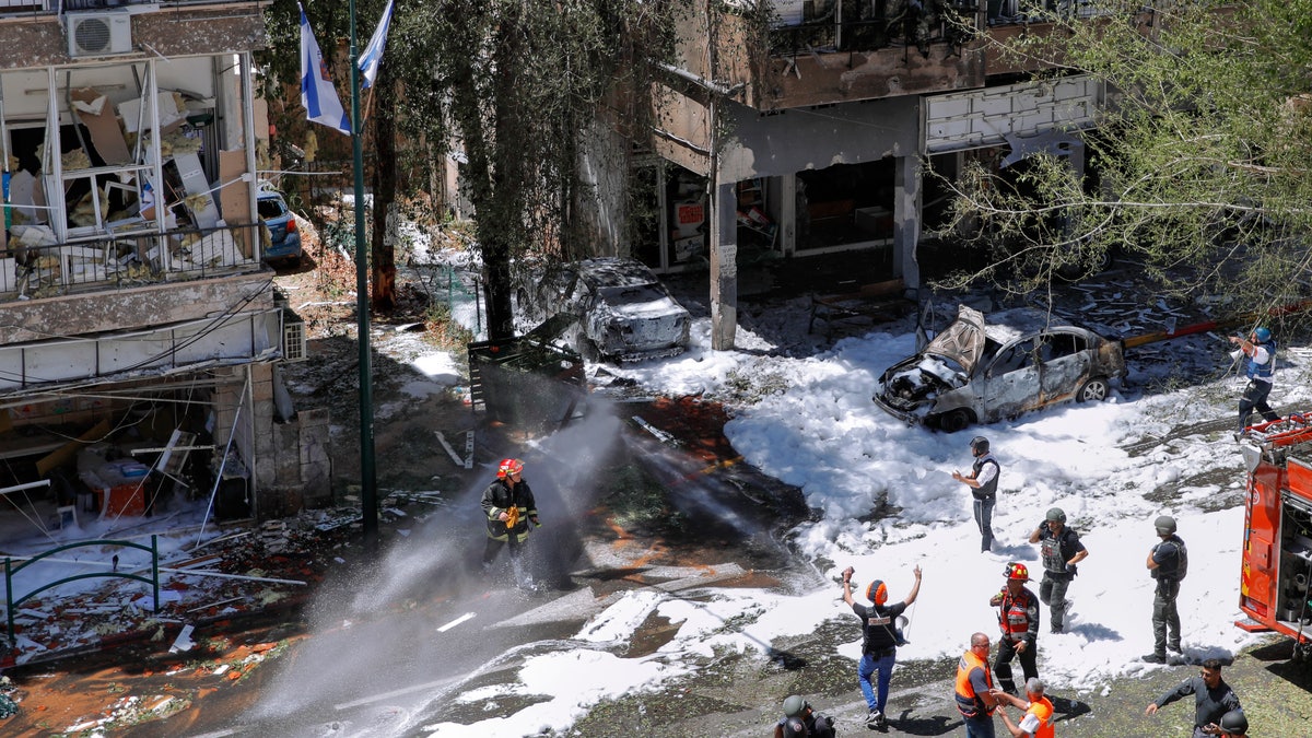 Israeli security forces and emergency services work on a site hit by a rocket fired from the Gaza Strip, in Ramat Gan, central Israel, Saturday, May 15, 2021. (AP Photo/Oded Balilty)