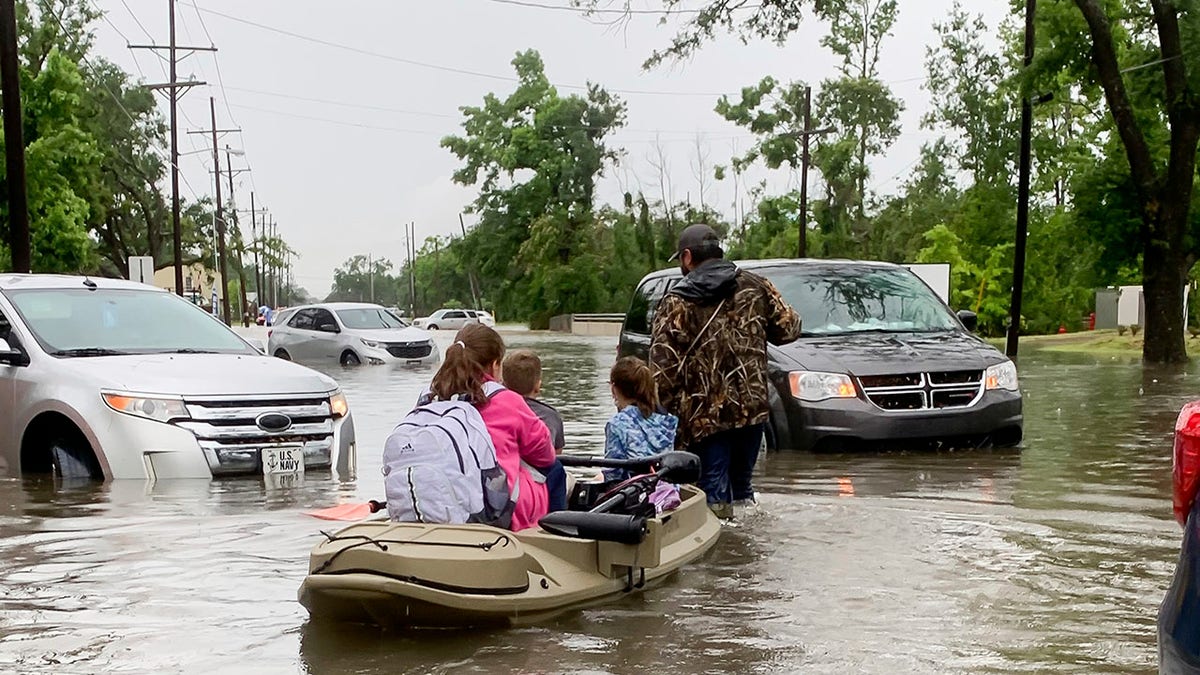 Parents use boats to pick up students from schools after nearly a foot of rain fell in Lake Charles, La., Monday, May 17, 2021. (Rick Hickman/American Press via AP)