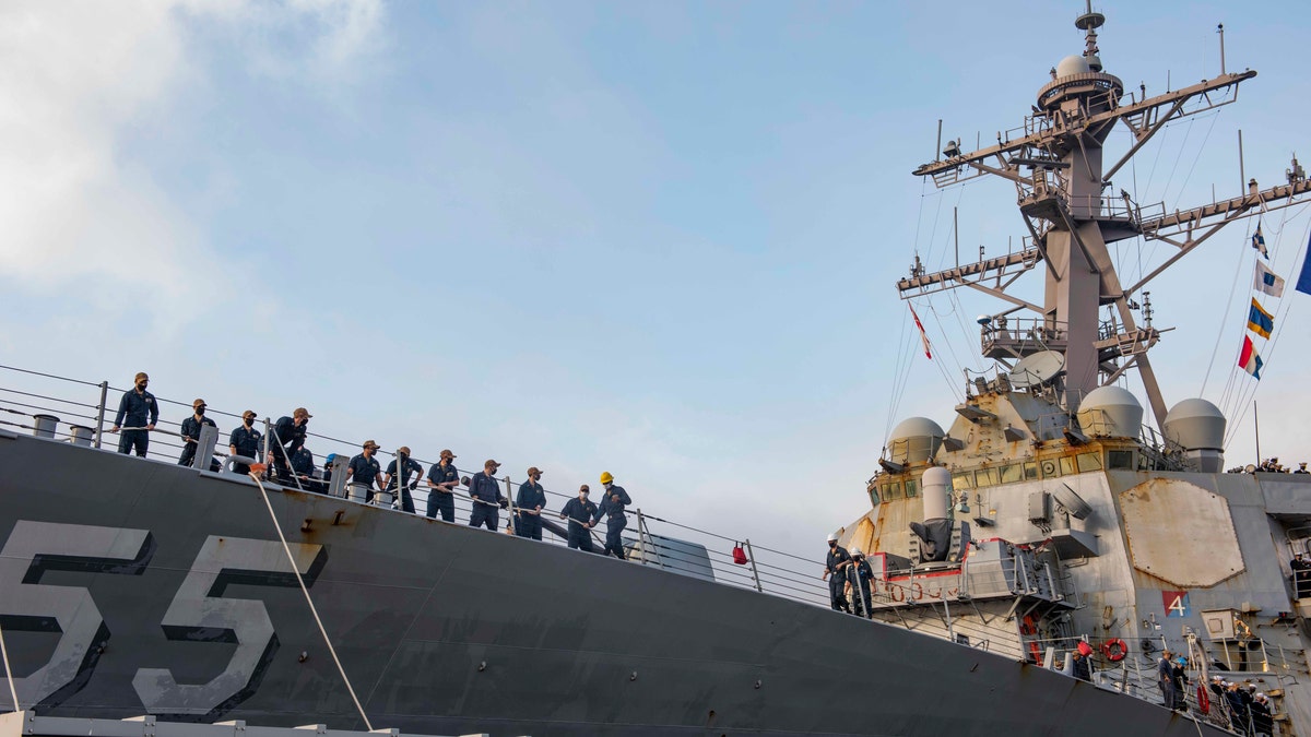 In this photo provided by the U.S. Navy, sailors aboard the guided missile destroyer USS Stout handle mooring lines during the ship's return to home port at Naval Station Norfolk, in Norfolk, Va., in this Oct. 12, 2020, photo. The USS Stout showed rust as it returned from the 210-day deployment. The rust was quickly removed and the ship repainted. But the rusty ship and its weary crew underscored the costly toll of deferred maintenance on ships and long deployments on sailors. (Spc. Jason Pastrick/U.S. Navy via AP)