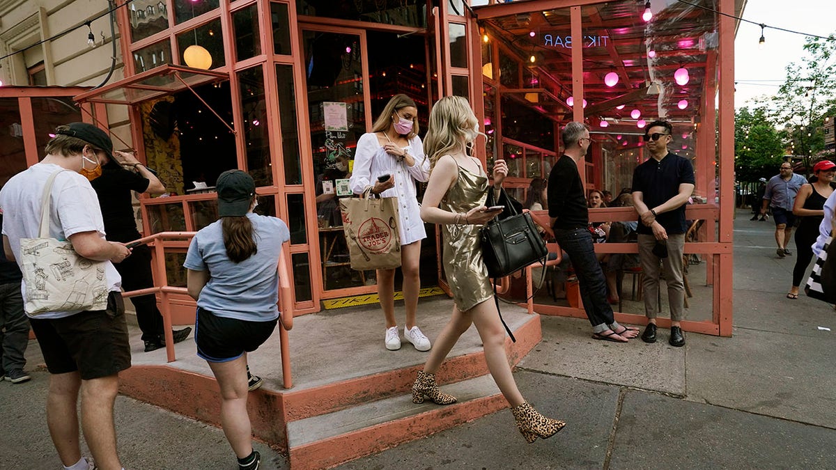 Patrons leave as others wait for a table at Tiki Bar on Manhattan's Upper West Side, Monday, May 17, 2021, in New York. Although the week was just beginning, the popular Upper West Side corner bar and restaurant was hopping Monday, perhaps in anticipation of Wednesday, when vaccinated New Yorkers will be able to shed their masks in most situations. Restaurants, shops, gyms and many other businesses can go back to full occupancy if all patrons are inoculated. (AP Photo/Kathy Willens)