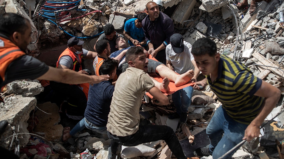 FILE - In this May 16, 2021, file photo, Palestinians rescue a survivor from the rubble of a destroyed residential building following deadly Israeli airstrikes in Gaza City. The Gaza Strip's already feeble health system is being brought to its knees by the fourth war in just over a decade. (AP Photo/Khalil Hamra, File)