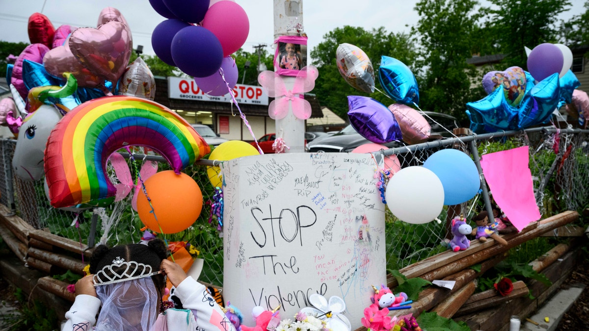 Aria Sherrod, 4, put on a tiara that was left at the memorial for Aniya Allen, 6, in Minneapolis, Wednesday, May 19, 2021. Minneapolis police confirmed that the 6-year-old girl shot in the head when her mother drove through what authorities believe was a shootout between rival gangs has died. (Aaron Lavinsky/Star Tribune via AP)
