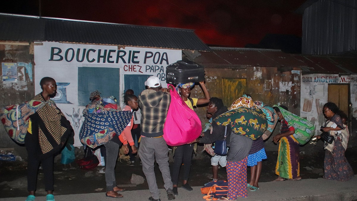 People flee with their belongings after the eruption of Mount Nyiragongo, in Goma, Congo, Saturday, May 22, 2021. Congo's Mount Nyiragongo erupted for the first time in nearly two decades Saturday, turning the night sky a fiery red and sending lava onto a major highway as panicked residents tried to flee Goma, a city of nearly 2 million. (AP Photo/Justin Kabumba)