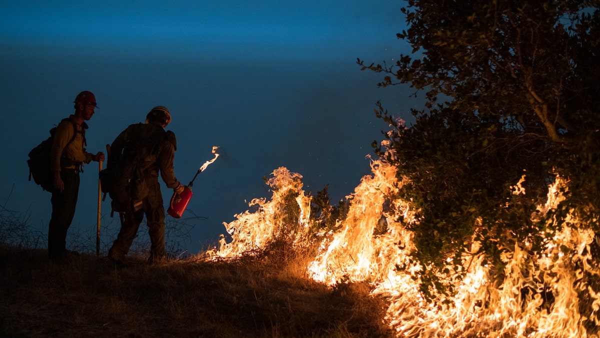 In this Sept. 11, 2020, file photo, firefighters light a controlled burn along Nacimiento-Fergusson Road to help contain the Dolan Fire near Big Sur, Calif.  (AP Photo/Nic Coury, File)