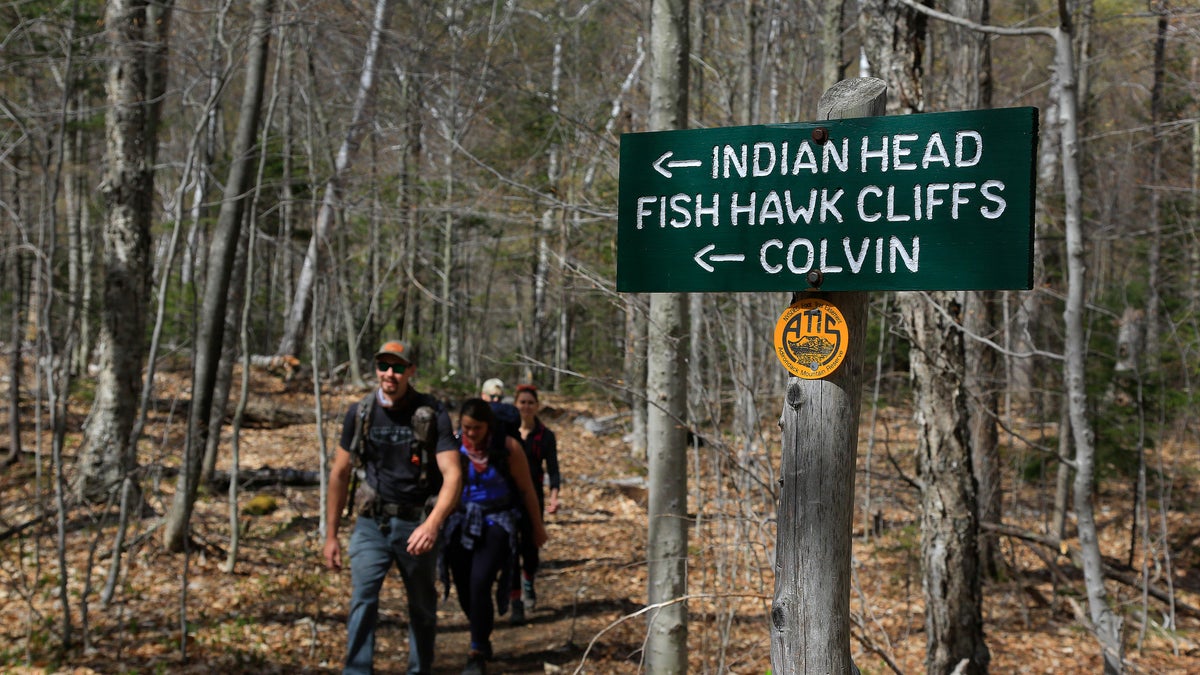 Hikers walk along the trail from Indian Head summit inside the Adirondack Mountain Reserve, Saturday, May 15, 2021, near St. Huberts, N.Y. A free reservation system went online recently to control the growing number of visitors packing the parking lot and tramping on the trails through the private land of the Adirondack Mountain Reserve. The increasingly common requirements, in effect from Maui to Maine, offer a trade-off to visitors, sacrificing spontaneity and ease of access for benefits like guaranteed parking spots and more elbow room in the woods. (AP Photo/Julie Jacobson)