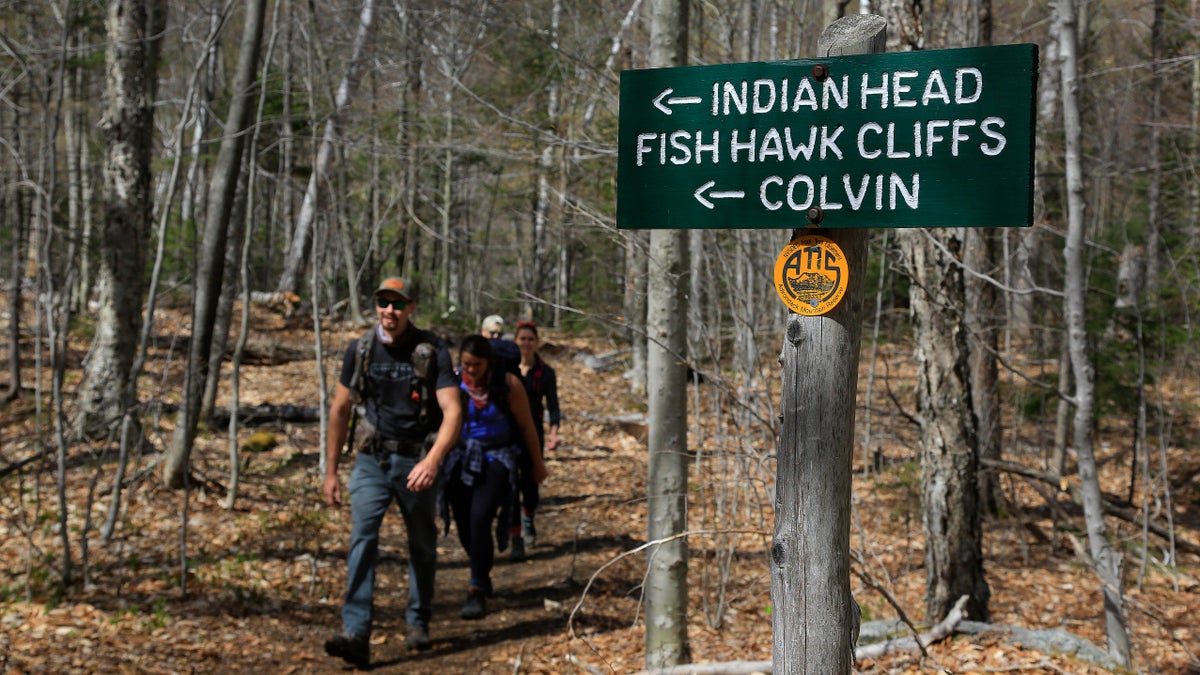 Hikers walk along the trail from Indian Head summit inside the Adirondack Mountain Reserve, Saturday, May 15, 2021, near St. Huberts, N.Y. A free reservation system went online recently to control the growing number of visitors packing the parking lot and tramping on the trails through the private land of the Adirondack Mountain Reserve. The increasingly common requirements, in effect from Maui to Maine, offer a trade-off to visitors, sacrificing spontaneity and ease of access for benefits like guaranteed parking spots and more elbow room in the woods. (AP Photo/Julie Jacobson)